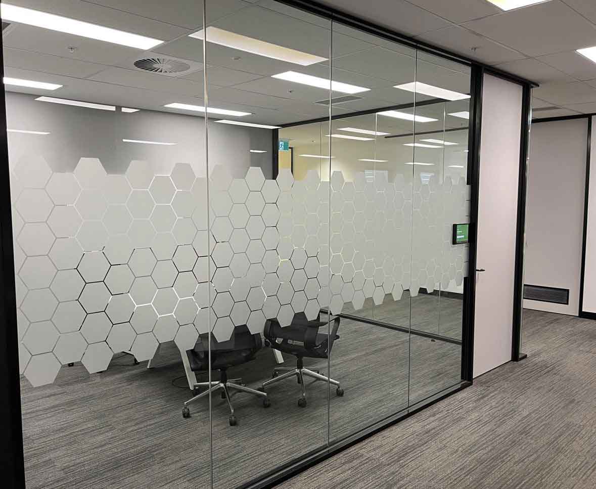 Modern office interior with glass walls and vinyl etch hexagonal pattern.
