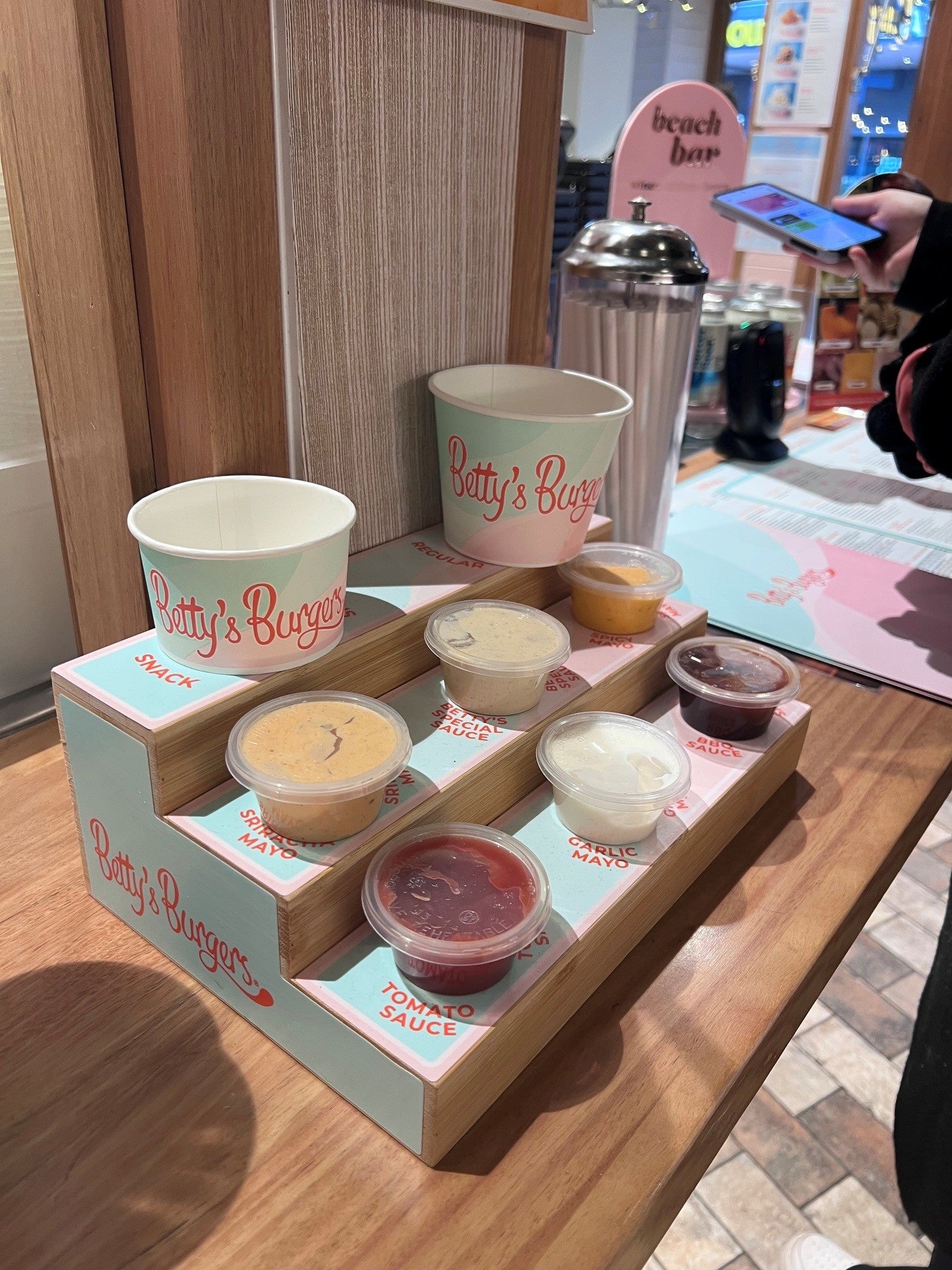 Bettys Burgers POS display showing sauce options available and chip cup sizes