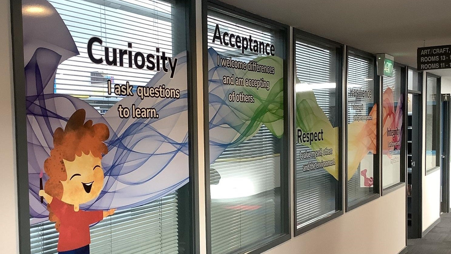 School posters on a window with characters and text about curiosity, acceptance, and respect, the school principles made as a window sign.