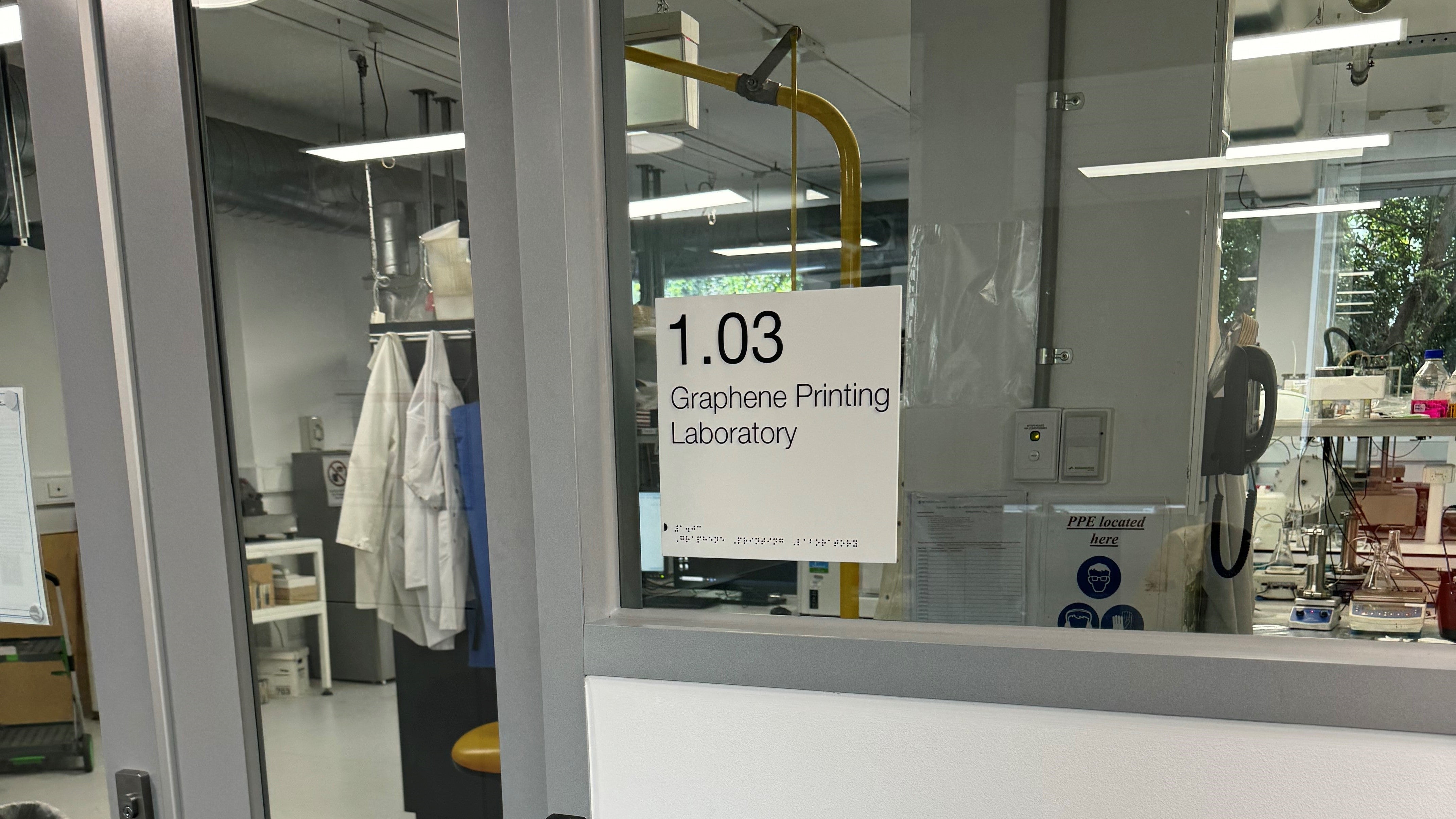 Glass door to a school laboratory with school room sign '1.03 Graphene Printing Laboratory' 