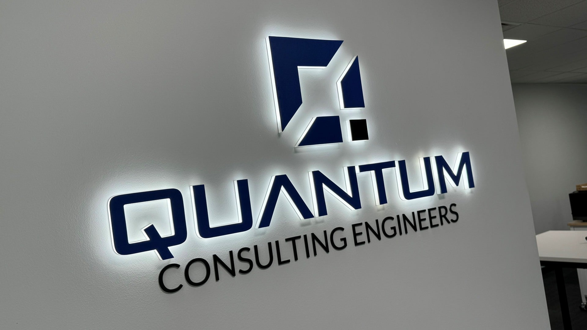 Quantum Consulting Engineers logo on a wall made as a 3D acrylic halo lit reception sign